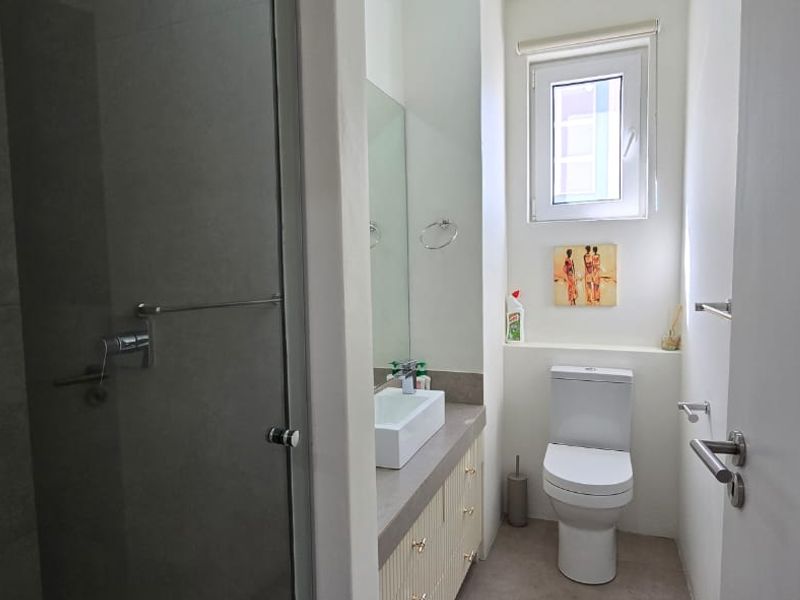 A modern bathroom featuring a glass-enclosed shower, a vanity with a vessel sink, and a clean, neutral aesthetic.