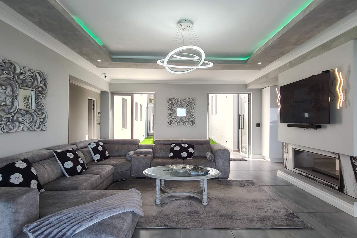 Modern living room featuring a recessed tray ceiling with ambient LED lighting, a built-in fireplace, and large sliding glass doors leading to the exterior.