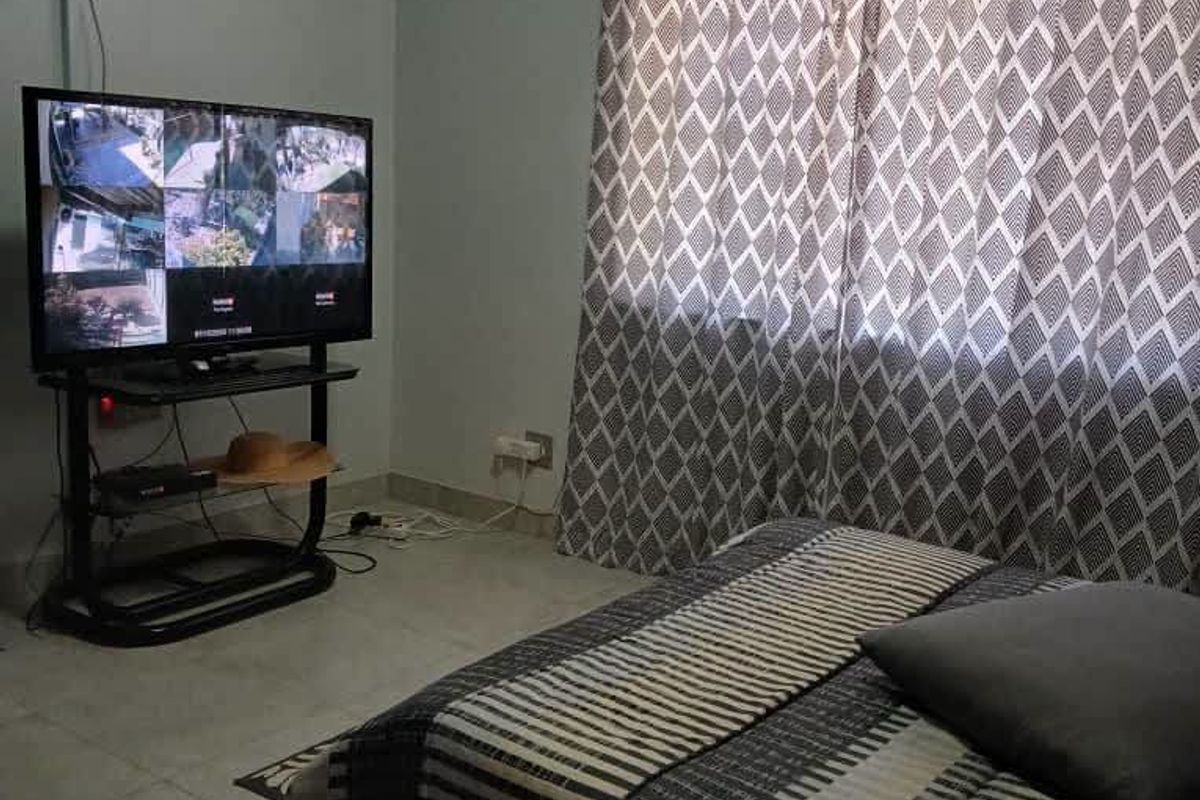 A functional bedroom featuring tiled flooring and a window with a curtain rod, providing a neutral base for potential interior updates.