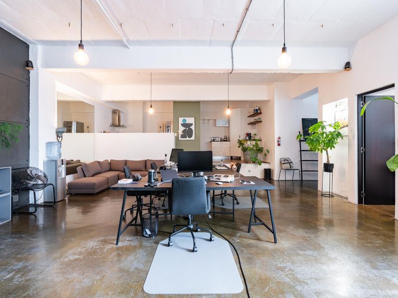 Spacious open-plan office area featuring polished concrete floors, exposed ceiling beams, and a functional integrated kitchen space.