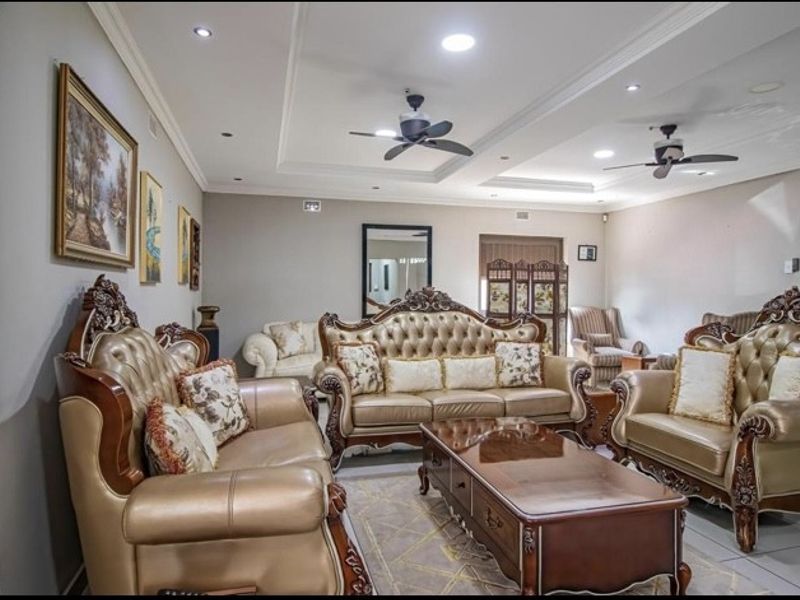 Spacious living room featuring recessed ceiling lighting, dual ceiling fans, and neutral tiled flooring with elegant cove molding.