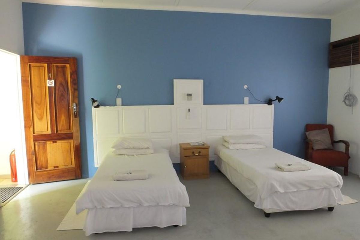 A guest bedroom featuring a built-in headboard, twin bed configuration, and a solid wood entrance door.