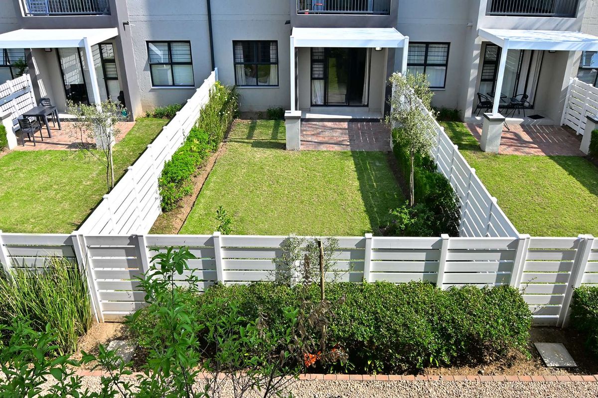A well-maintained private rear garden featuring a paved patio, pergola, and neat white timber fencing, providing a pleasant outdoor living space.