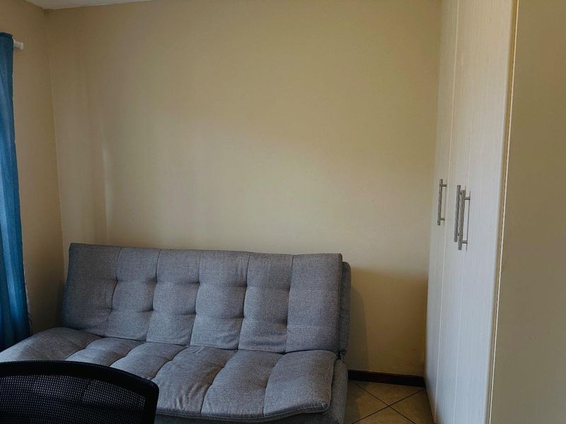 A bedroom featuring neutral wall finishes, tiled flooring, and a built-in wardrobe with modern handles.