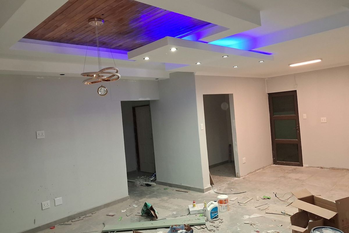 Spacious living area featuring a modern recessed ceiling with timber inlay and integrated LED lighting, currently undergoing final finishing touches.