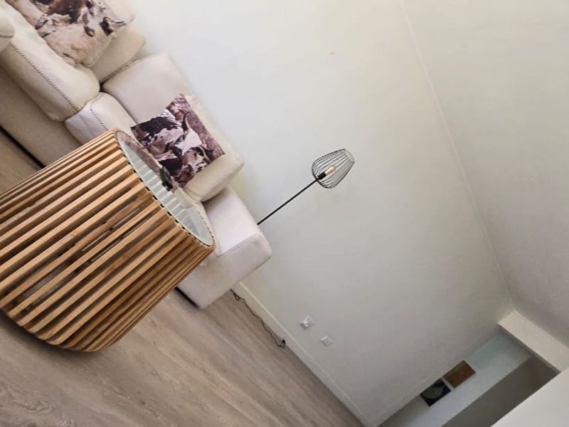 A living room area featuring light-toned laminate flooring and neutral wall finishes, captured from a tilted perspective.