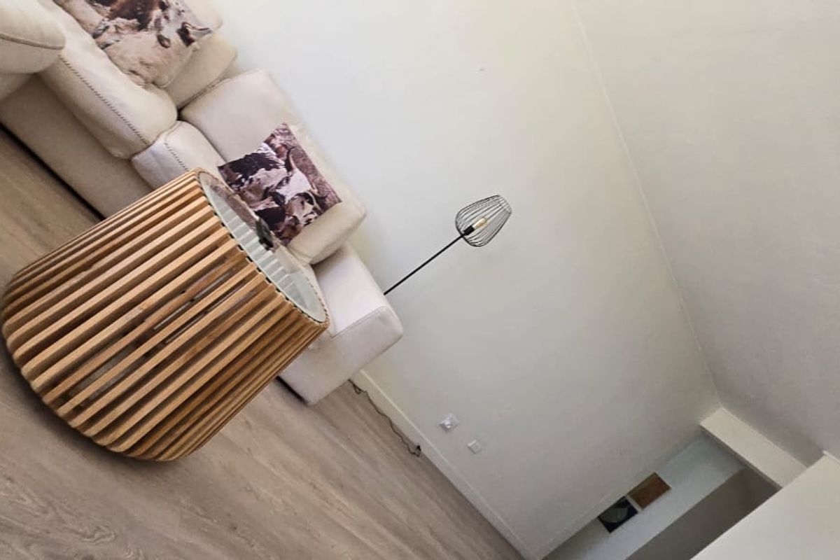 A living room area featuring light-toned laminate flooring and neutral wall finishes, captured from a tilted perspective.