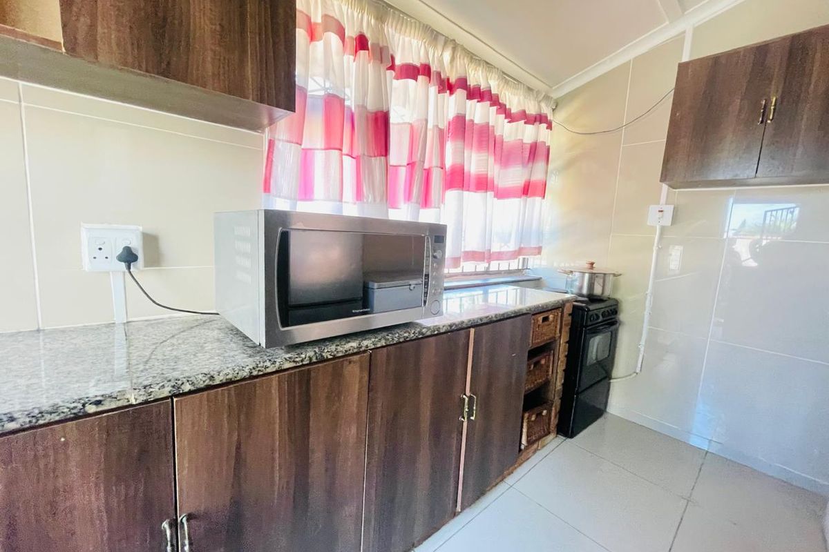 A functional kitchen featuring dark wood cabinetry, granite countertops, tiled backsplash, and tiled flooring, providing a practical workspace for daily cooking.