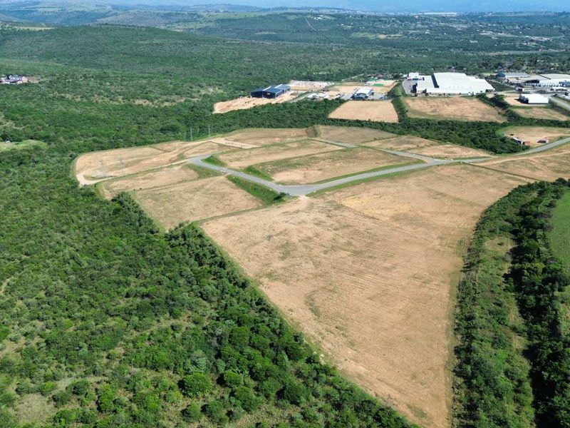 Aerial view of a large industrial development site featuring cleared land plots and established access roads within a natural landscape.