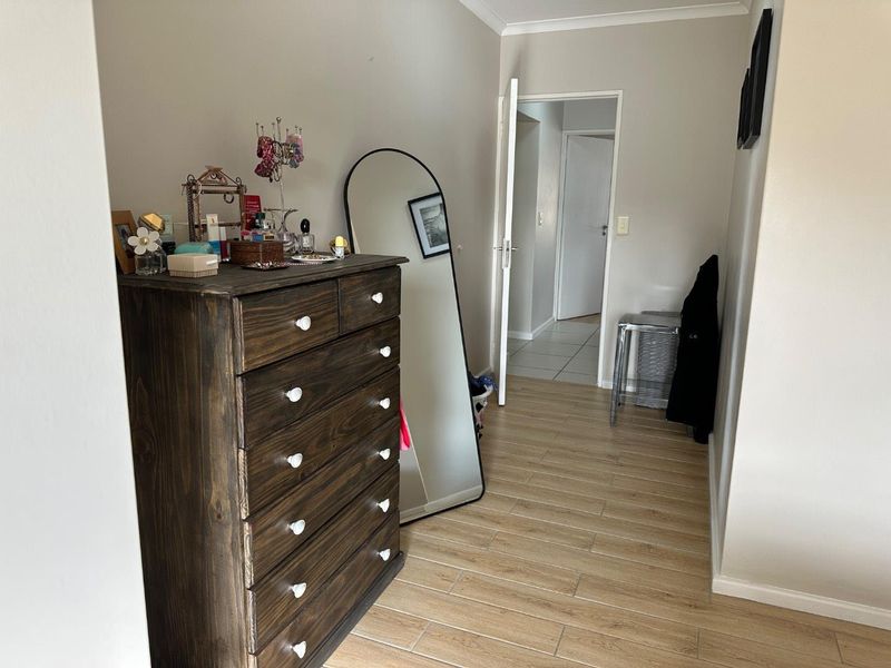 A well-maintained hallway featuring light-toned tiled flooring and neutral wall finishes, providing access to adjacent rooms within the apartment.