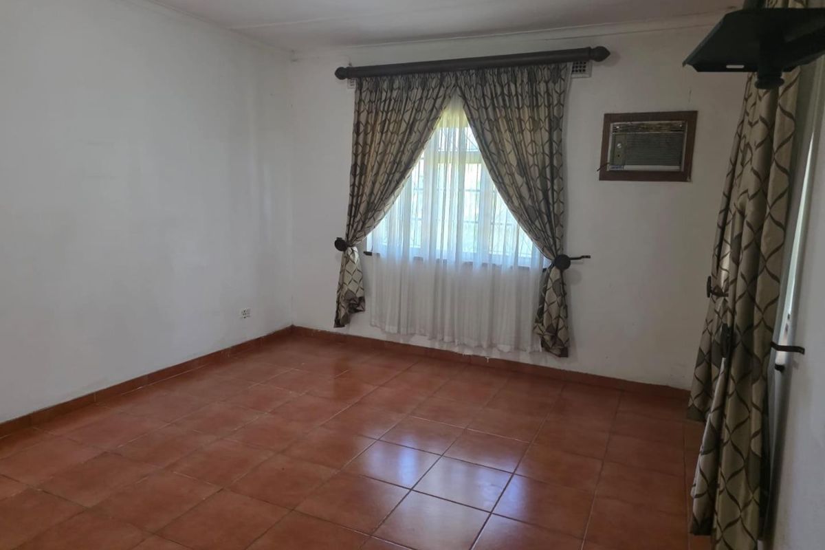 An empty bedroom featuring ceramic tile flooring and a built-in window air conditioning unit, offering a blank canvas for potential updates.