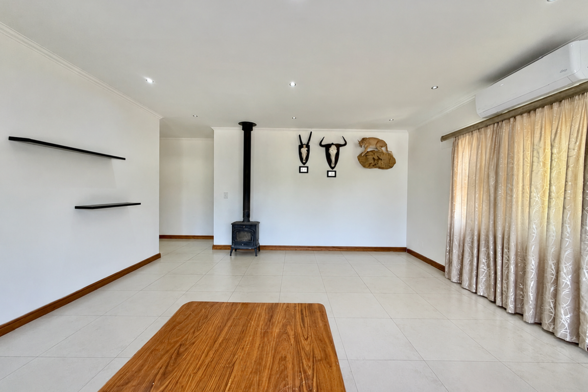 Spacious living area featuring tiled flooring, a freestanding fireplace, recessed lighting, and a wall-mounted air conditioning unit.