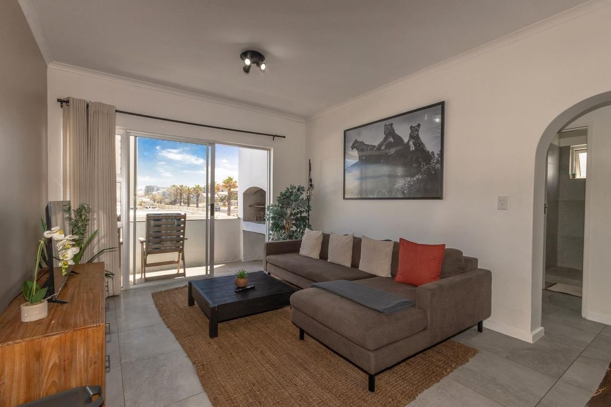 A bright living room featuring tiled floors, an arched doorway, and a sliding glass door providing access to an outdoor balcony area.