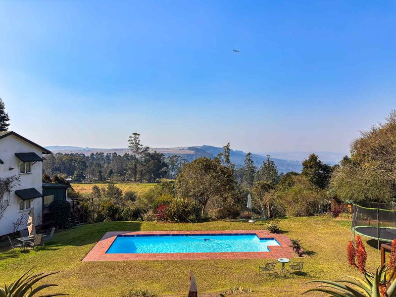 Outdoor swimming pool area featuring brick coping, set within a spacious garden with expansive scenic landscape views.