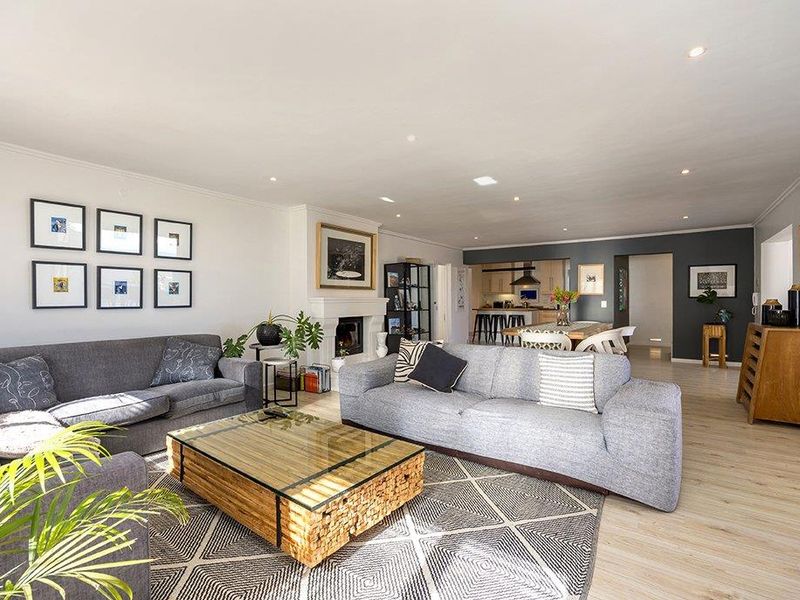 Spacious open-plan living area featuring a fireplace, recessed lighting, and seamless flow into the kitchen, finished with modern laminate flooring.