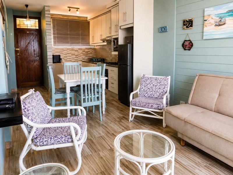 Open-plan living and kitchen area featuring wood-look floor tiles, built-in cabinetry, and a functional kitchen layout with a tiled backsplash.