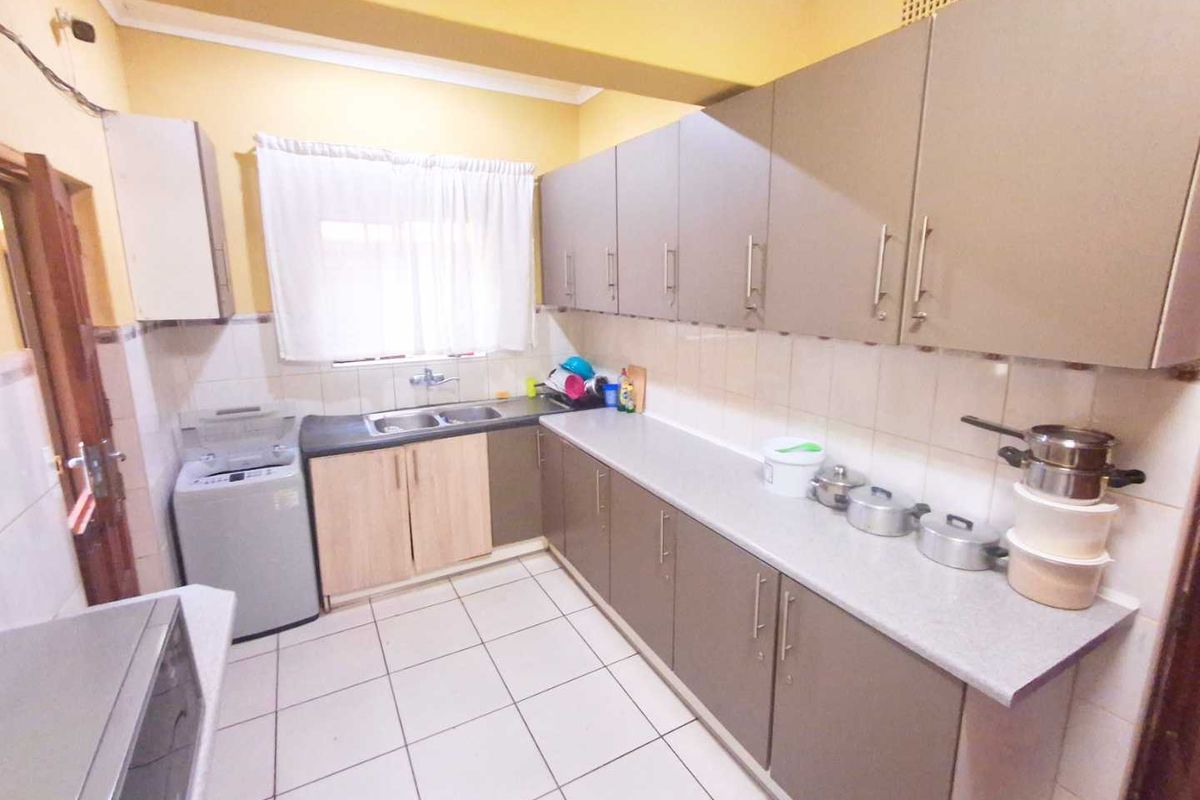 Functional kitchen featuring ample built-in cabinetry, laminate countertops, a double basin sink, and tiled flooring with a tiled backsplash.