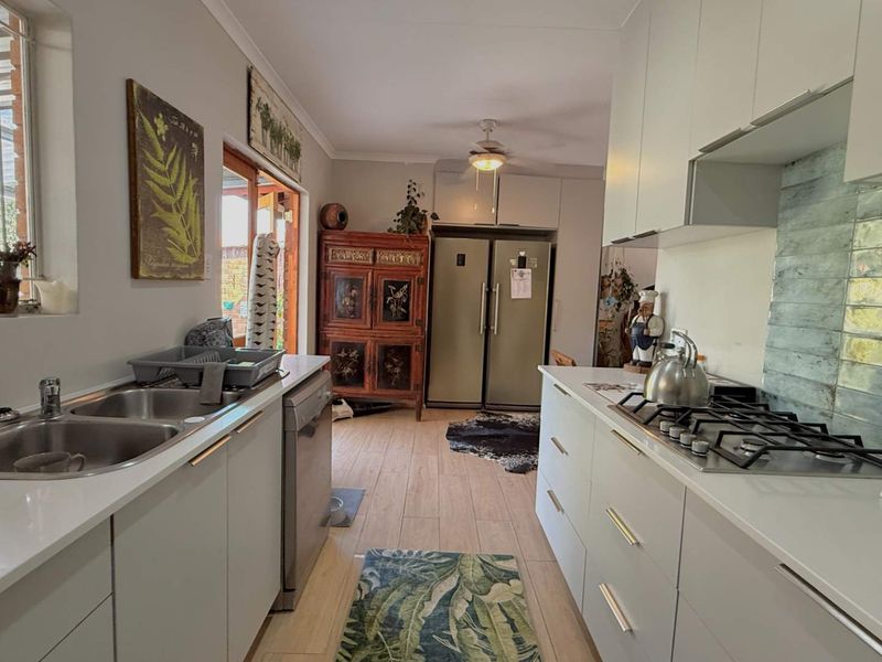 Modern galley-style kitchen featuring stone countertops, a gas hob, ample built-in cabinetry, and a double bowl stainless steel sink.