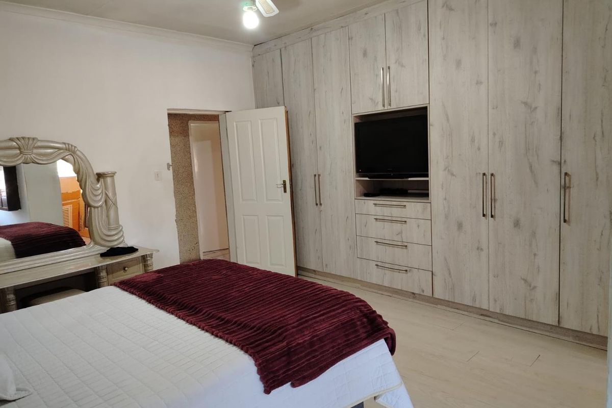 Spacious bedroom featuring extensive built-in cabinetry with integrated shelving and a ceiling fan.