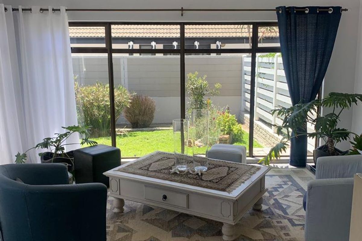 A bright living room featuring large floor-to-ceiling windows that provide a clear view of the private rear garden.