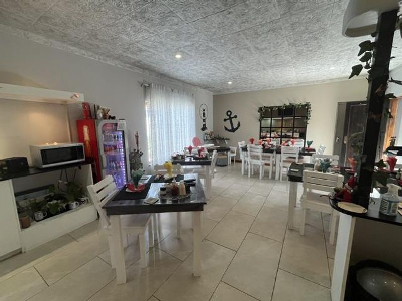 An open-plan dining area featuring large format floor tiles and a textured ceiling, providing a functional space for dining and social gatherings.