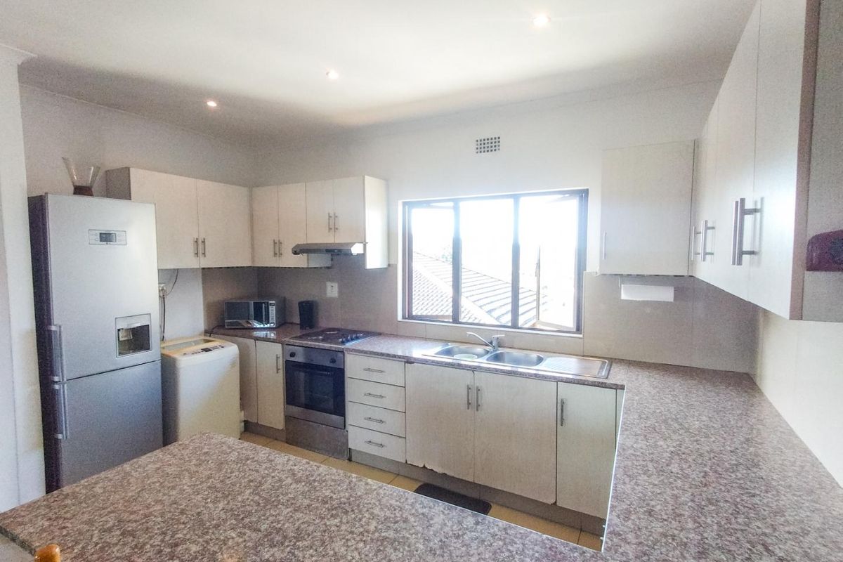 Functional kitchen featuring granite countertops, ample built-in cabinetry, stainless steel sink, and integrated oven with extractor fan.