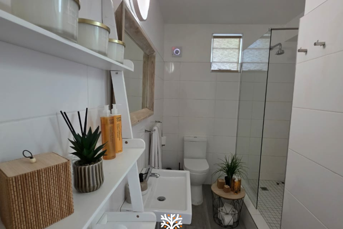 Modern bathroom featuring a walk-in shower with glass screen, wall-mounted basin, toilet, and clean white wall tiling.