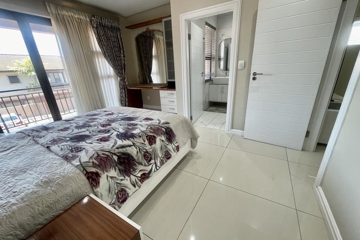 Spacious bedroom featuring tiled flooring, built-in vanity unit, and direct access to an en-suite bathroom and private balcony.