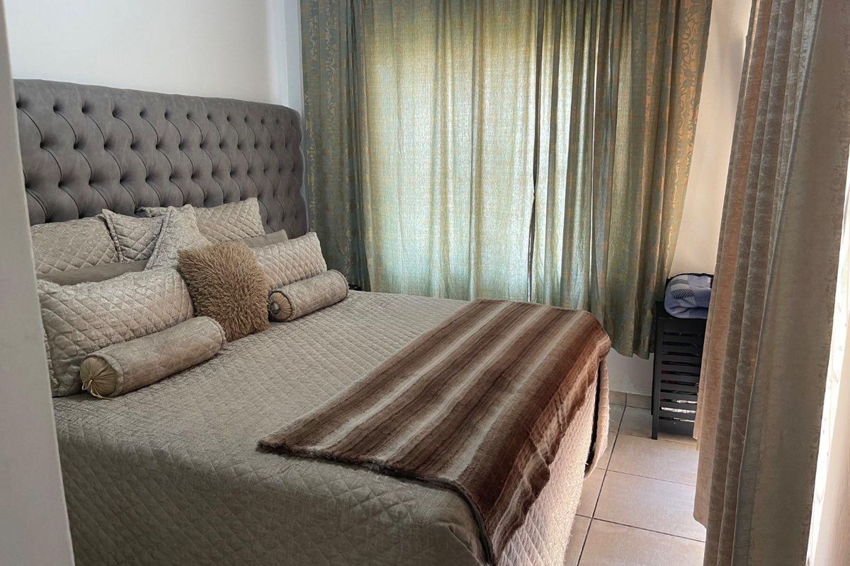 A cozy bedroom featuring tiled flooring and large window treatments, providing a comfortable and private sleeping space.