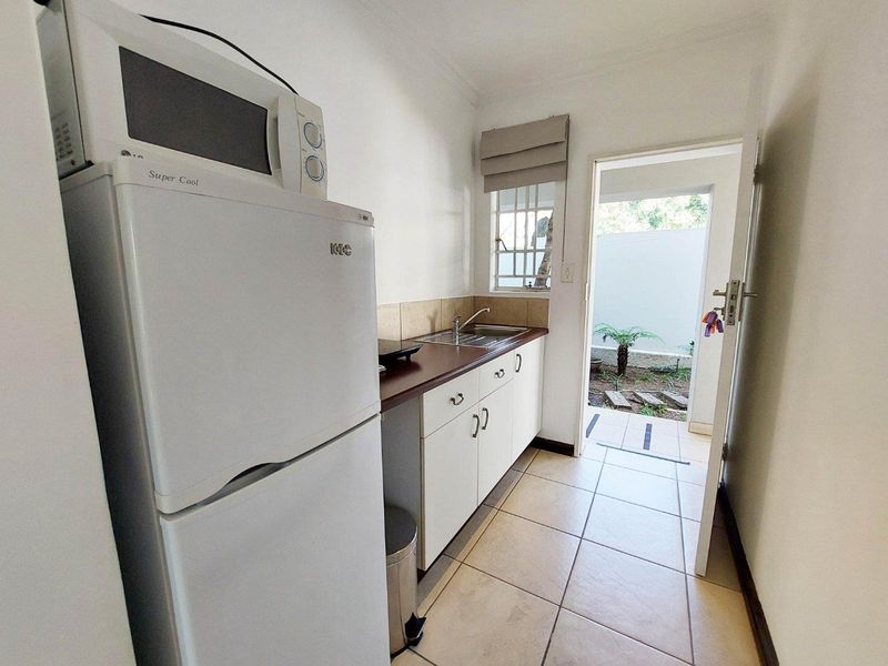 Compact scullery area featuring built-in cabinetry, laminate countertops, a stainless steel sink, and direct access to an outdoor courtyard.
