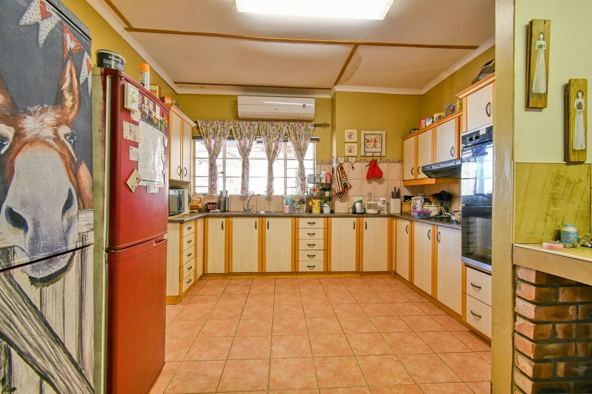 A functional kitchen featuring U-shaped cabinetry, built-in oven, extractor fan, and tiled flooring, offering a practical layout for daily meal preparation.