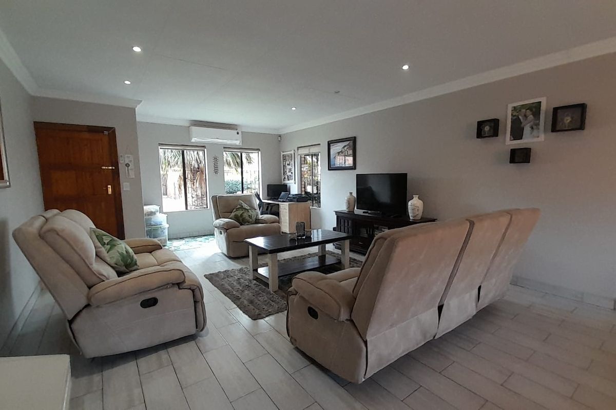 Spacious living room featuring tiled flooring, recessed downlighting, and a wall-mounted air conditioning unit.