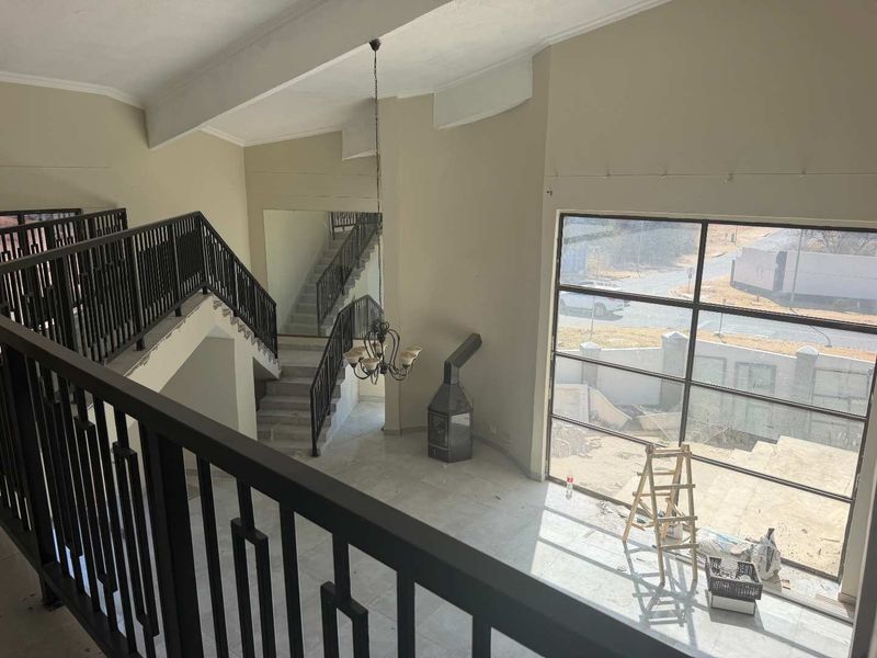 Spacious double-volume living area featuring a central staircase, large windows, and a freestanding fireplace, currently in an unfinished state.