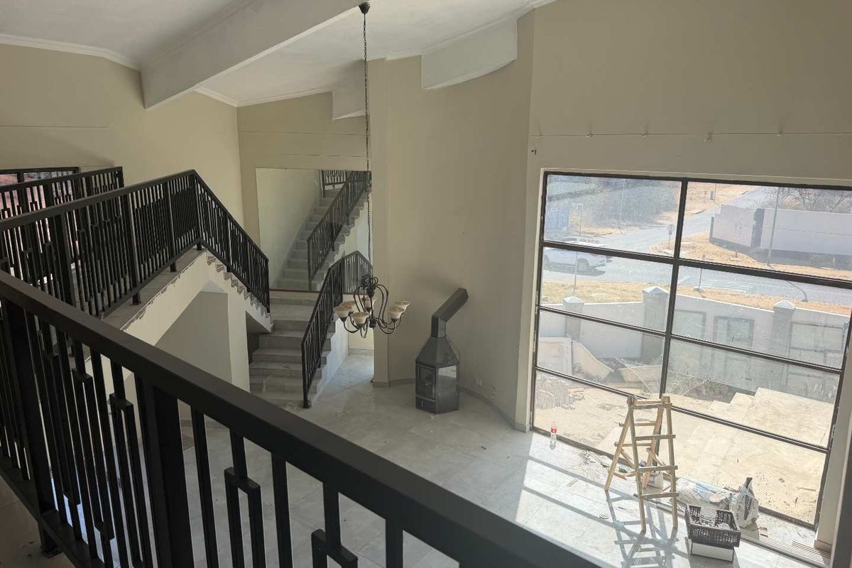 Spacious double-volume living area featuring a central staircase, large windows, and a freestanding fireplace, currently in an unfinished state.