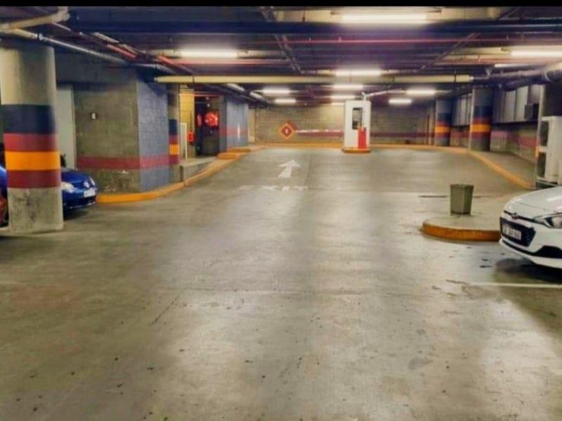 Underground parking garage featuring concrete flooring, structural columns, and a security boom gate exit.