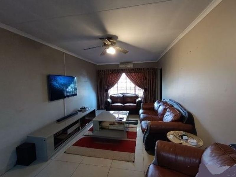 A living room featuring tiled flooring, a ceiling fan, and an integrated air conditioning unit, providing a functional and comfortable space.