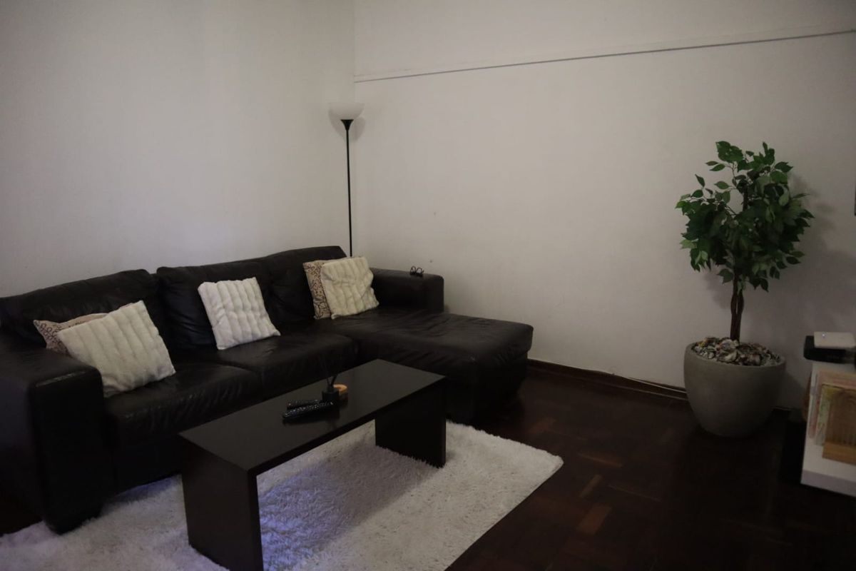 A living room featuring dark parquet flooring and plain white walls, providing a neutral foundation for interior design.