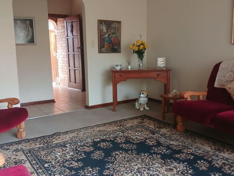A living room area featuring carpeted flooring, an arched entryway, and a tiled transition area leading to a timber door.