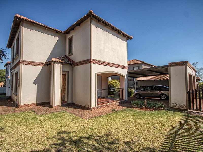 A two-story residential home featuring a covered patio, carport, and a well-maintained lawn area.