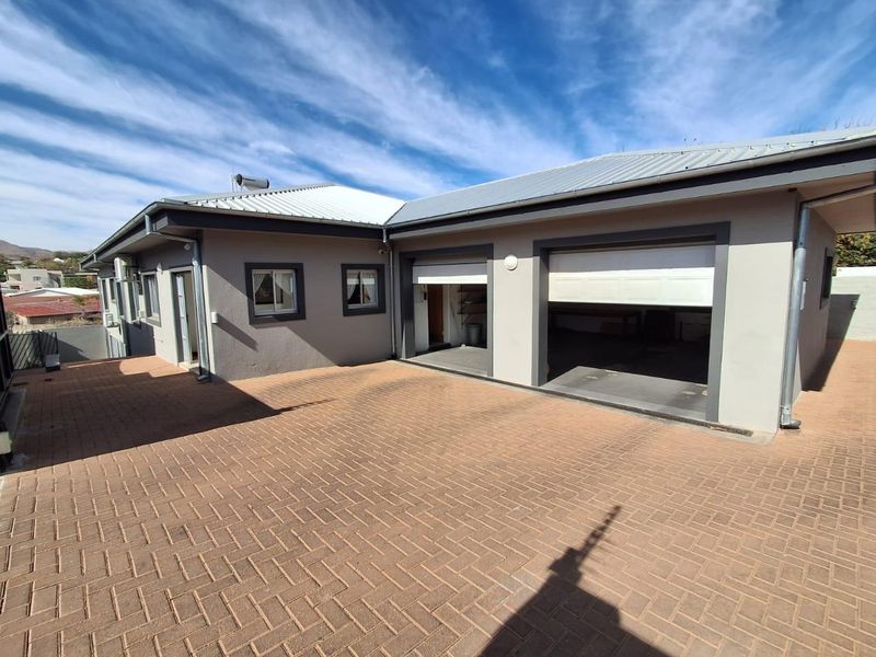 A well-maintained exterior view of the property featuring a paved driveway, double garage, and solar geyser installation.