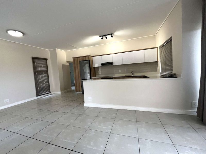 An open-plan living and kitchen area featuring modern cabinetry, tiled flooring, and neutral finishes, providing a clean and versatile space.