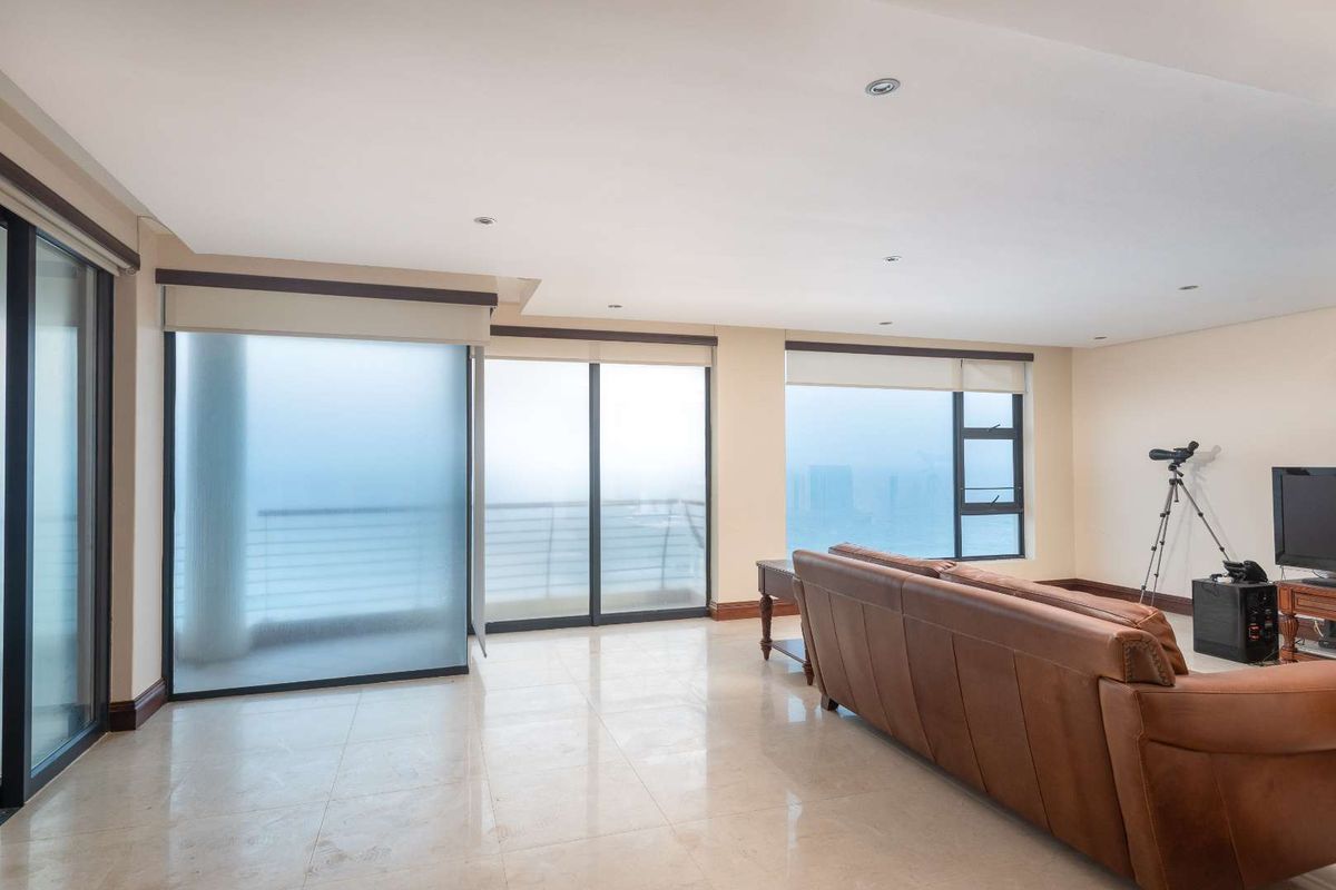 Spacious living area featuring large sliding glass doors, polished tile flooring, and recessed ceiling lighting, offering ample natural light and access to the balcony.