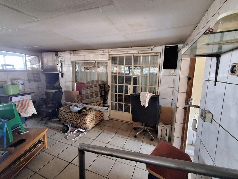 Enclosed patio area featuring tiled flooring, wall tiling, and a built-in braai, offering potential for a functional outdoor entertainment space.