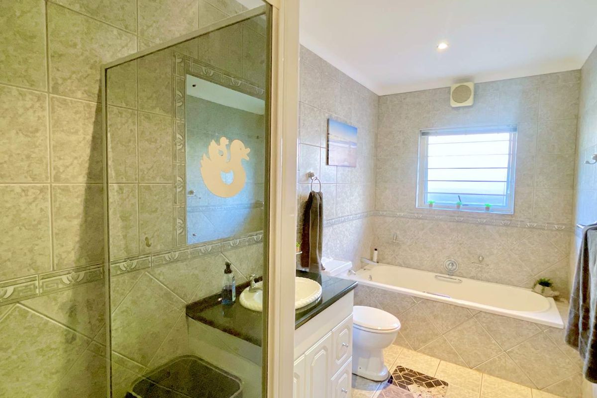A functional bathroom featuring a built-in vanity, a separate shower enclosure, and a bathtub with tiled walls and flooring.