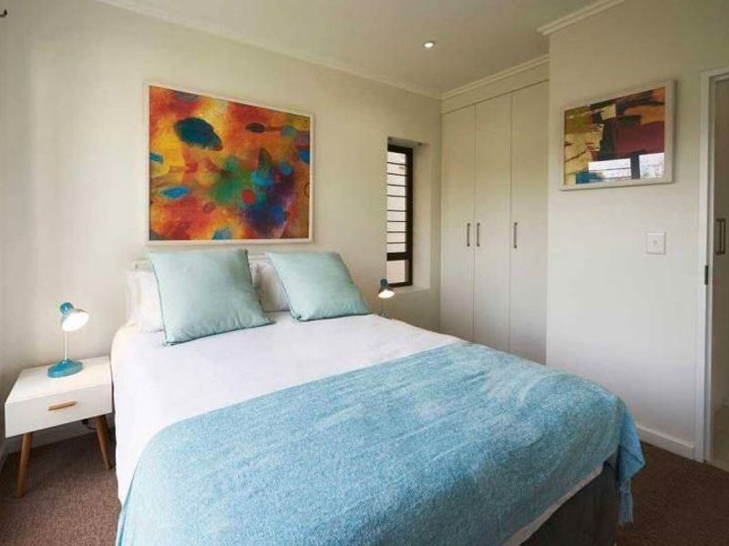 A well-maintained bedroom featuring built-in cupboards, recessed downlighting, and neutral carpeted flooring, offering a clean and functional living space.