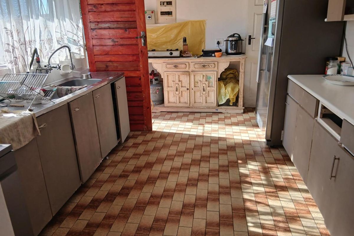 A functional kitchen featuring a stainless steel sink, built-in cabinetry, and tiled flooring, offering a practical layout with potential for modernization.