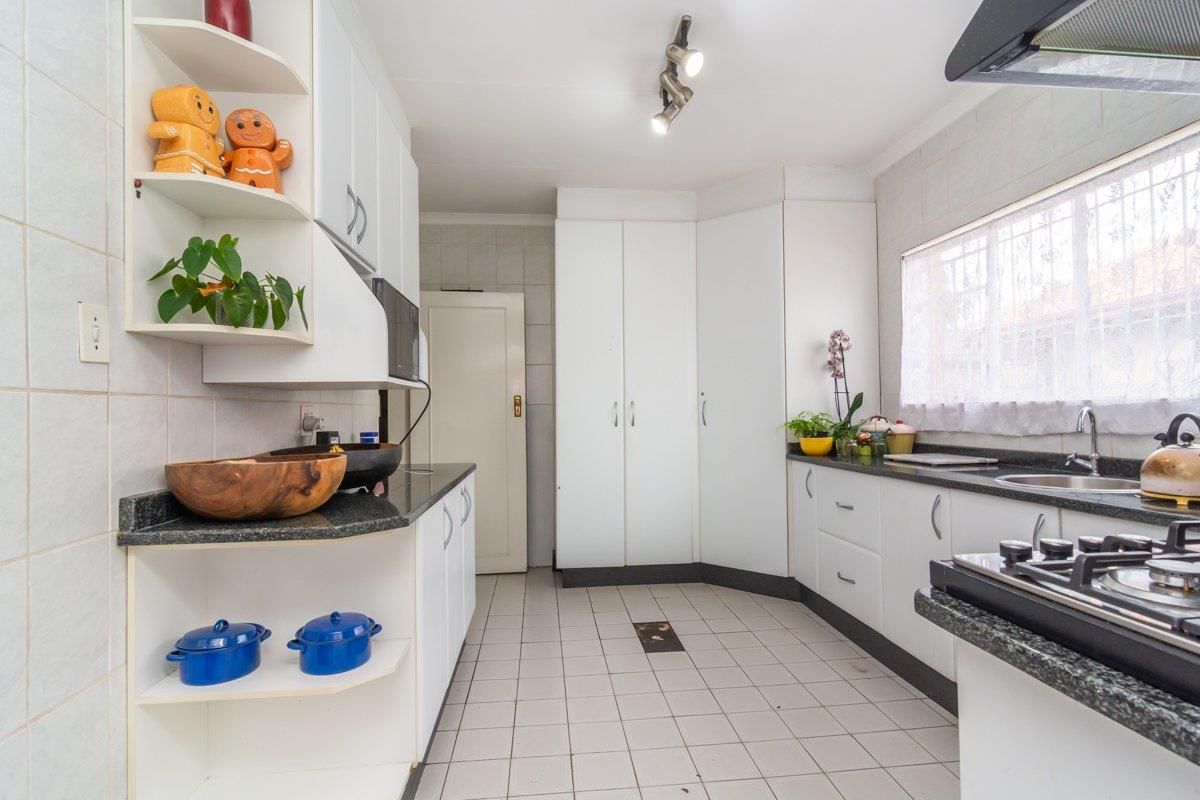 A functional kitchen featuring white cabinetry, granite countertops, a gas hob, and tiled finishes throughout.