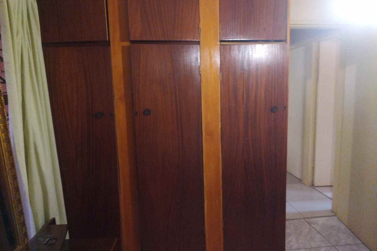 A bedroom featuring built-in wooden cabinetry with overhead storage compartments, providing functional storage space within the room.