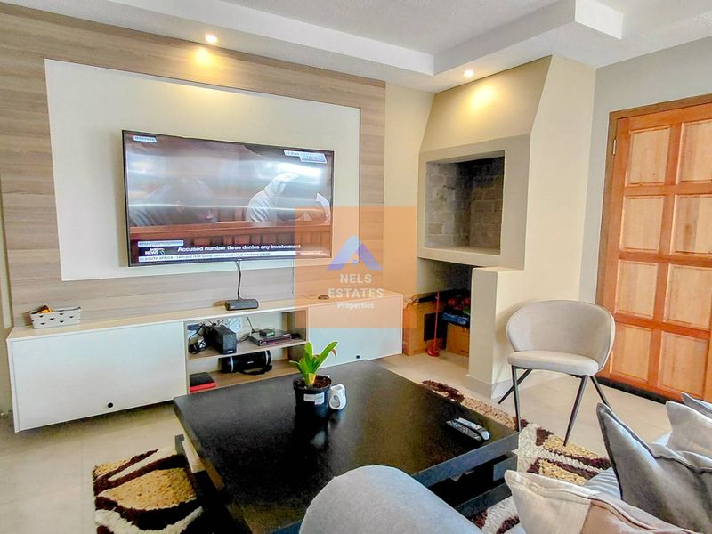 A living room featuring a built-in media unit, a fireplace, and recessed ceiling lighting.