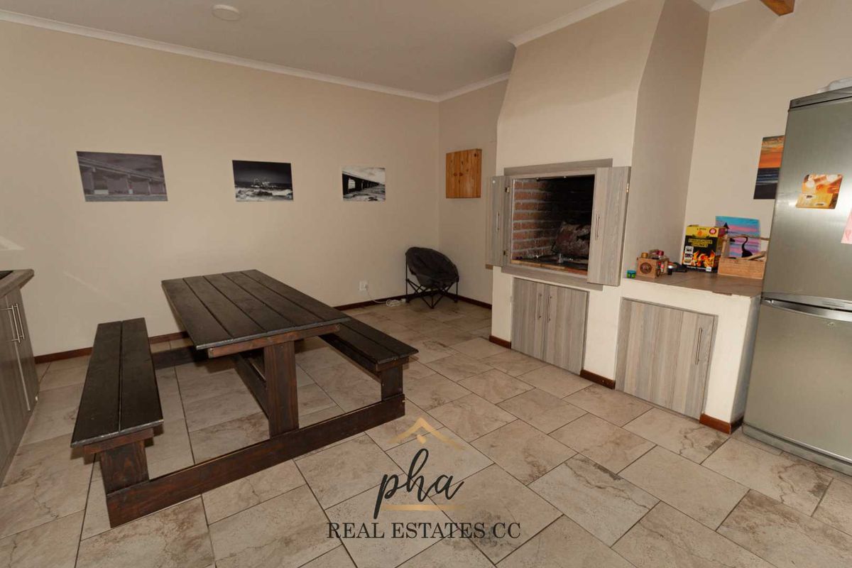 An indoor entertainment area featuring a built-in brick braai, tiled flooring, and cabinetry, providing a functional space for social gatherings.